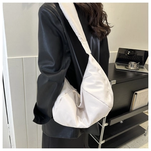 Close-up of white quilted puffer crossbody bag worn with a black leather jacket