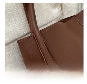 Close-up of brown leather tote showing reinforced stitching and fine textured finish
