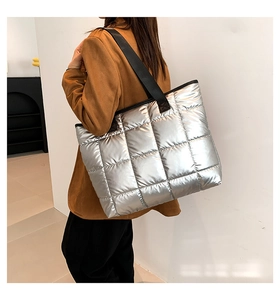 Detalle del bolso tote acolchado plateado con acabado metálico y correas de tejido negro