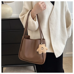 Detailed shot of brown PU leather tote bag with light-colored plush pendant detail