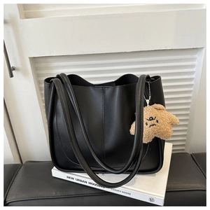 Detail view of black leather tote bag with vertical stitching and cute star plush charm