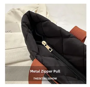 Detail of high-quality golden metal zipper puller on a black quilted tote bag