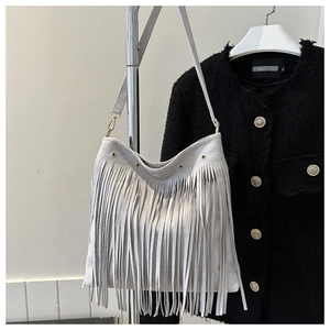 Detailed close-up of a light gray suede fringe hobo bag with bohemian tassel decoration