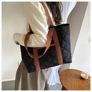 Detailed view of the large black quilted nylon tote bag with stylish brown shoulder straps