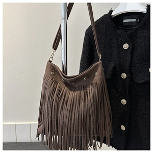 Detailed view of brown tassel shoulder bag with gold metal rings and wide strap