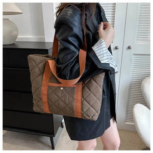 Detailed side view of quilted tote bag with orange straps worn by a model in a blazer