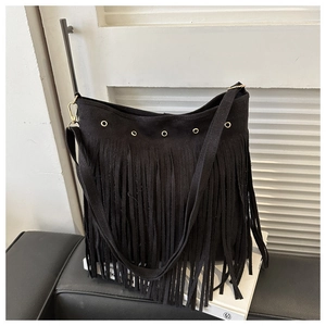 Detail of black suede tote bag featuring retro gold metal eyelets and long decorative fringe