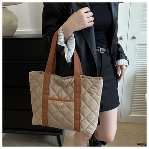 Detail shot of khaki quilted tote bag featuring brown straps and a gold snap button pocket