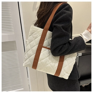 Close-up of white quilted tote bag featuring large diamond stitching and brown nylon straps
