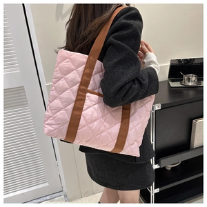 Detailed close-up of a pink quilted tote bag with brown straps styled on a grey blazer