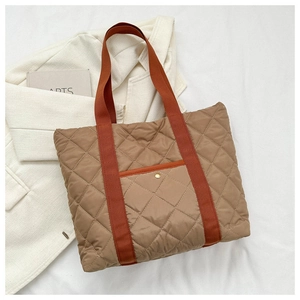 Detail of quilted tote bag with golden snap button pocket and two-tone fabric handles