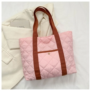 Close-up of pink quilted puffer tote bag with brown canvas straps and snap pocket detail
