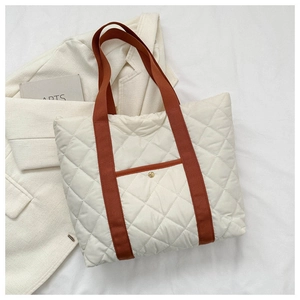 Detail of quilted oxford tote bag with orange handles and gold buckle pocket