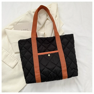 Close-up of black quilted nylon tote bag with orange contrast straps and snap pocket