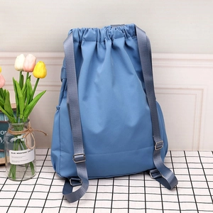 Detail of blue nylon drawstring bucket bag with adjustable grey shoulder straps