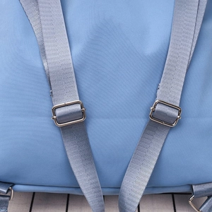 Detail of blue nylon backpack featuring silver metal adjustment buckles and durable straps