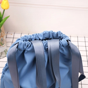 Detail of blue nylon drawstring bucket bag with sturdy grey woven shoulder straps