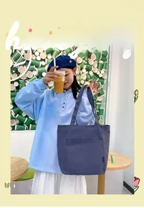 Close-up of deep blue canvas tote bag with front pocket shown in a creative studio setting