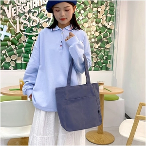 Deep blue canvas tote bag with front pocket detail in a trendy coffee shop setting