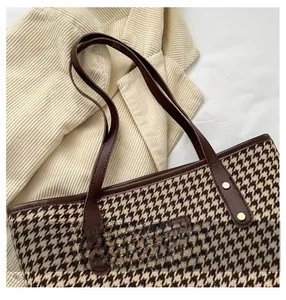 Gros plan du sac cabas à motif pied-de-poule avec poignées en cuir marron et rivets