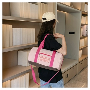 Detailaufnahme der rosa-braunen Sporttasche mit Webriemen in Innenraum-Ambiente