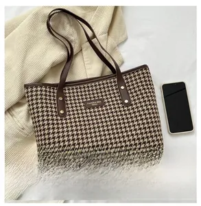 Détail du sac cabas rétro à carreaux avec poignées en cuir marron et logo de marque
