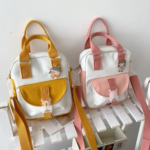 Cute Korean style contrast canvas crossbody bag with cartoon pin on white wooden stand