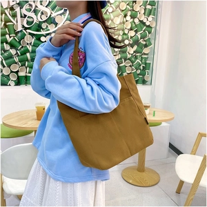 Close-up of caramel canvas tote bag with wide shoulder strap and side pocket in cafe setting