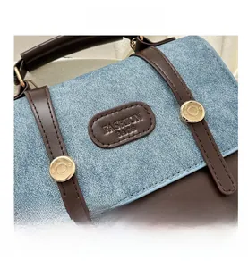 Detail aus blauem Denim und braunem Leder mit goldenen Nieten am Retro-Rucksack