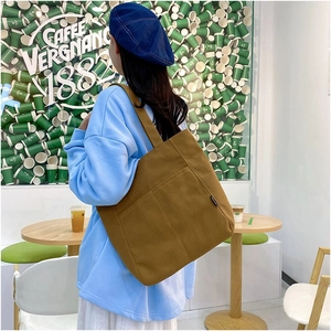 Brown canvas tote bag detail featuring spacious side pockets and sturdy shoulder straps
