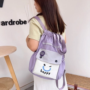 Detail of purple nylon drawstring bucket bag showing contrast pocket and smiley face logo