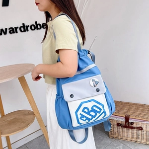 Detail view of stylish blue and white nylon drawstring backpack with snap pocket and logo