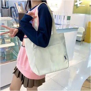 Detail of white canvas tote bag with thick material, wide straps and side label
