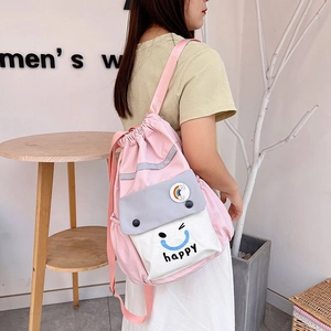 Detail view of pink nylon drawstring backpack with gray pocket and happy face logo