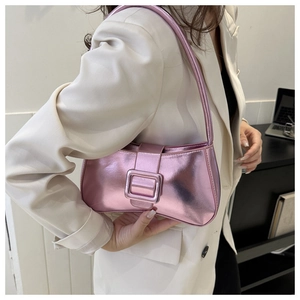 Primer plano del bolso de hombro rosa metalizado con hebilla sobre traje beige