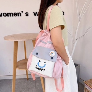 Detail of pink drawstring backpack featuring a white pocket with happy slogan and rainbow badge