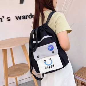 Detail view of contrast color nylon drawstring bucket backpack worn by model on shoulder