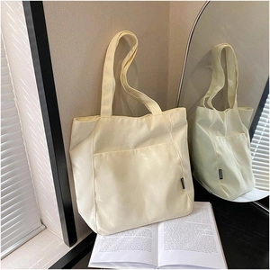Detail view of beige canvas tote bag showing thick texture and large front pocket
