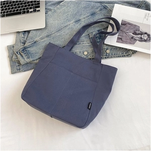 Detail of dark blue canvas tote bag with front pockets for students and office workers
