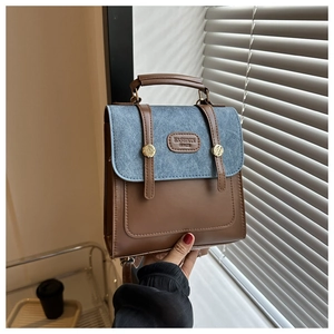 Detail des Vintage-Rucksacks aus braunem Leder und blauem Denim mit Metallschnalle