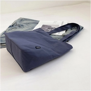 Detailed view of the navy blue canvas tote bag fabric texture and fashion label