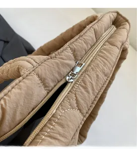 Close-up of smooth metal zipper and quilted diamond texture on khaki nylon tote bag