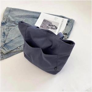 Detail of dark blue canvas tote bag featuring double front pockets and fabric texture