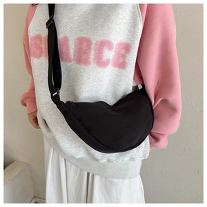 Detail of black crescent moon crossbody bag with adjustable shoulder strap worn by model