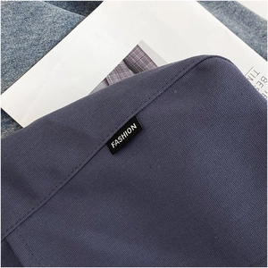 Detail of navy blue canvas tote bag with a white Fashion woven label and twill texture