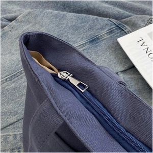 Close-up of a silver zipper on a durable blue canvas tote bag showing fine stitching