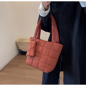 Detail of a caramel quilted nylon tote bag with a matching small pouch for versatile use