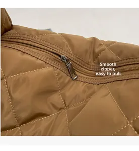 Close-up of smooth silver metal zipper on brown quilted tote bag with diamond pattern
