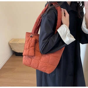 Detail of burnt orange quilted tote bag with honeycomb pattern and mini zipper pouch