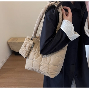 Detailed close-up of quilted beige tote bag showing square stitching and side coin purse